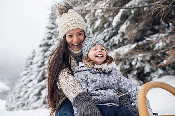 Mère et sa fille en train de rire sur une luge l'hiver