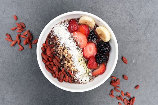 bol vu de dessus avec baies de goji noix de coco râpée et morceaux de fruits